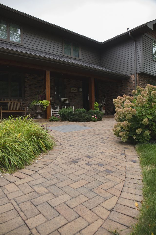 There is a brick walkway leading to the front of the house.