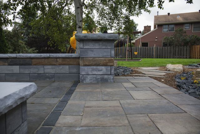 A brick walkway leading to a brick wall in a backyard.