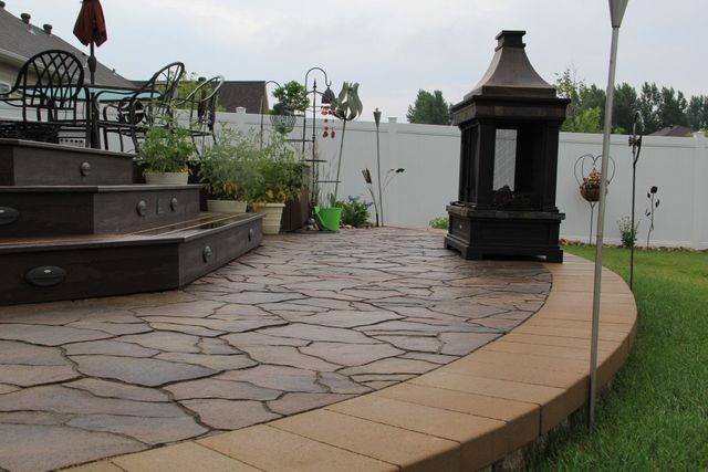 A patio with a fireplace and stairs in the backyard