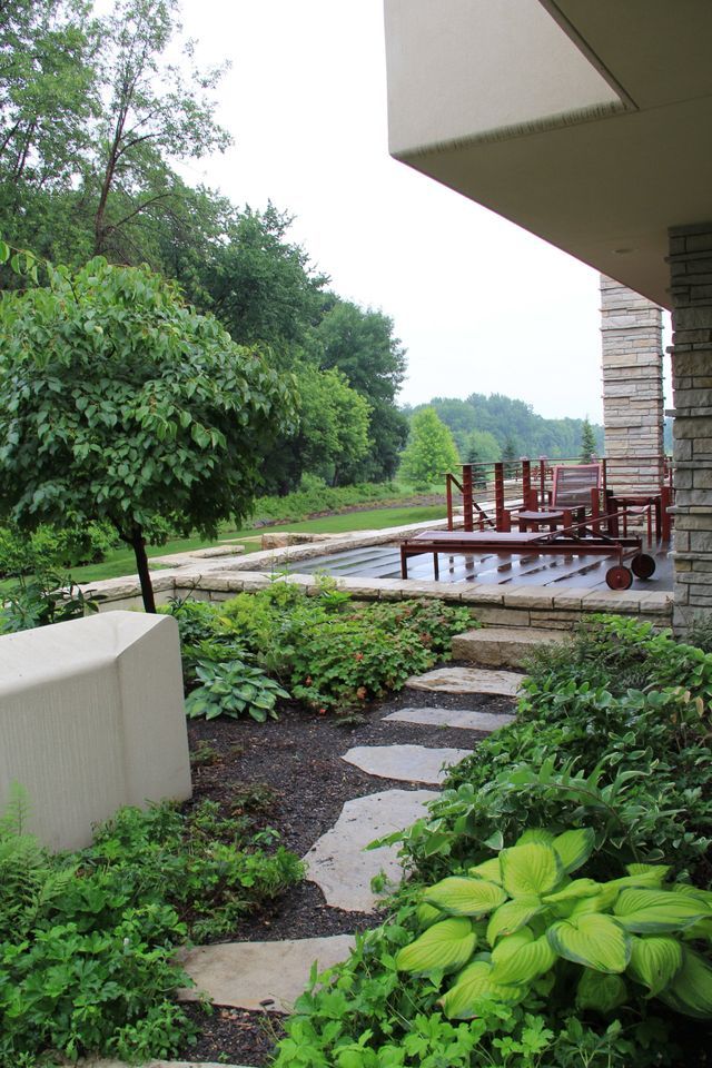 A stone walkway leading to a swimming pool in a garden.
