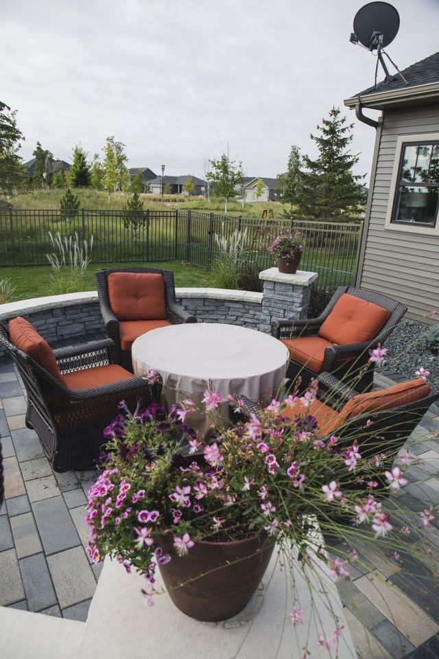 A patio with a table and chairs and a pot of flowers.