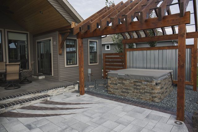 There is a hot tub under a pergola in the backyard of a house.