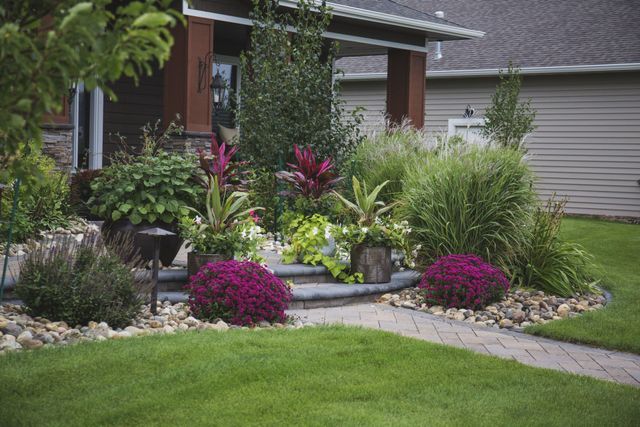 A house with a lush green lawn and a garden in front of it.