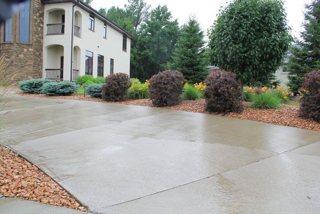 A concrete driveway with a house in the background