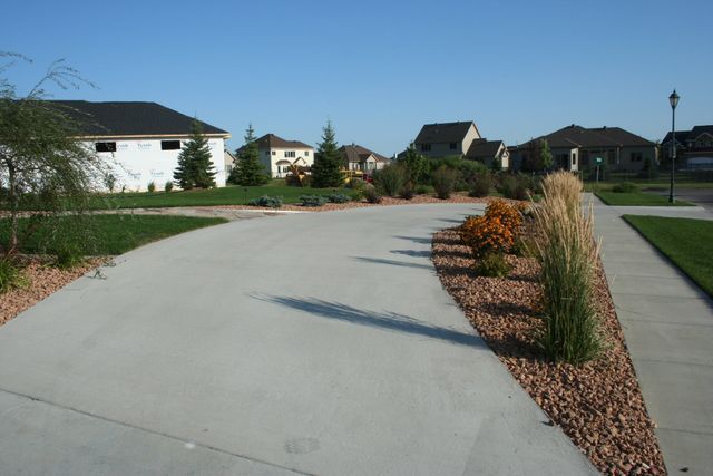 A concrete driveway in a residential area with houses in the background