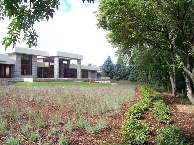 A large house sits in the middle of a lush green field