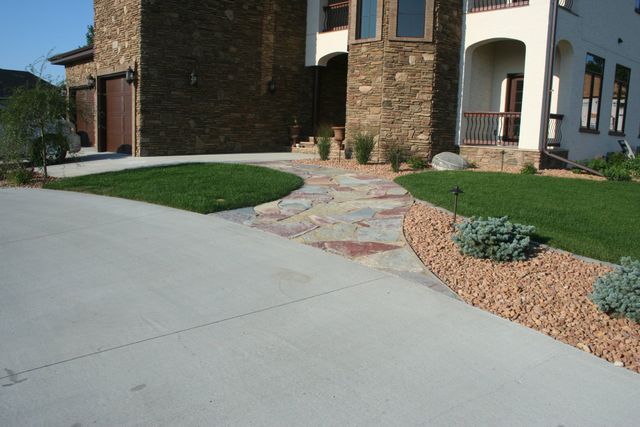 A stone house with a concrete driveway leading to it