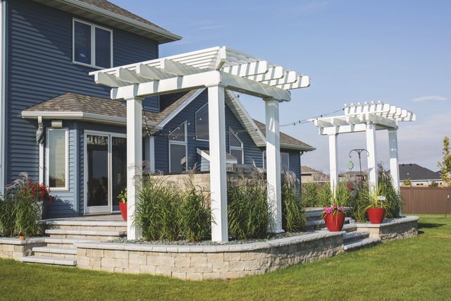 A blue house with a white pergola in front of it
