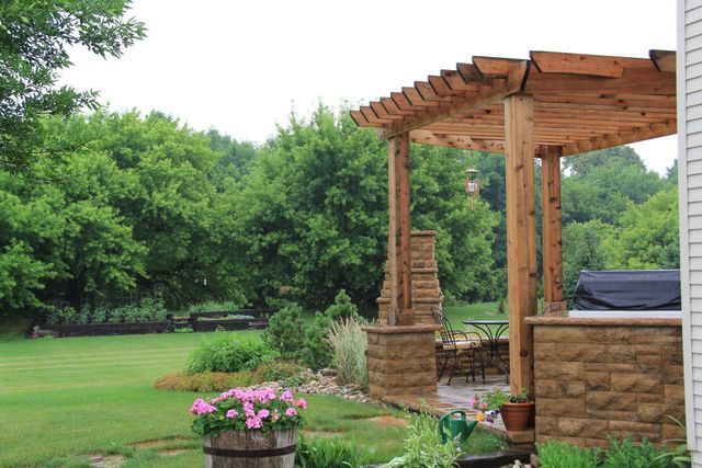 A wooden pergola is sitting in the middle of a lush green yard.