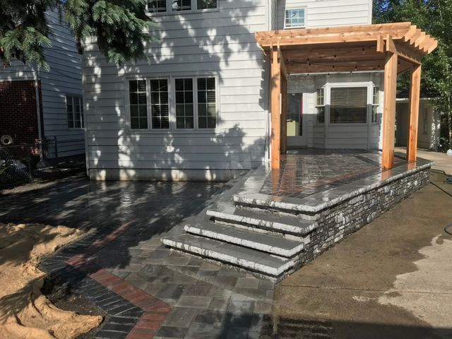 A white house with a patio and stairs in front of it.