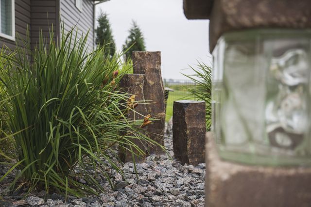 A garden with rocks and plants in front of a house.
