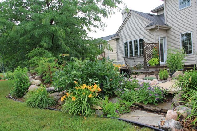 A house with a lot of plants and flowers in front of it