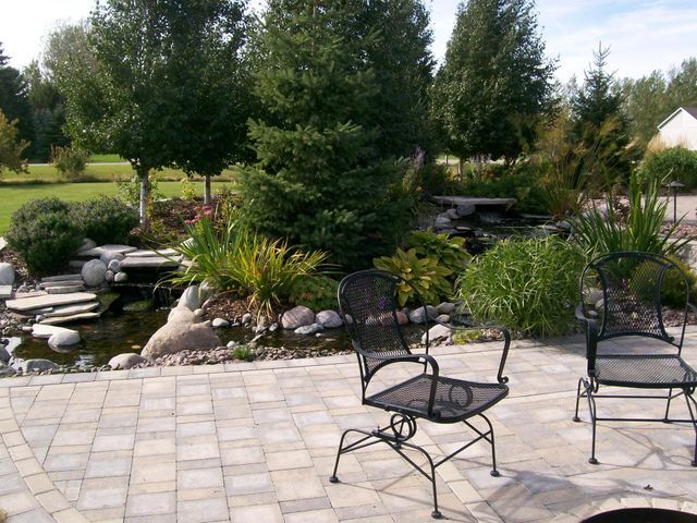 A patio with chairs and a fire pit with trees in the background