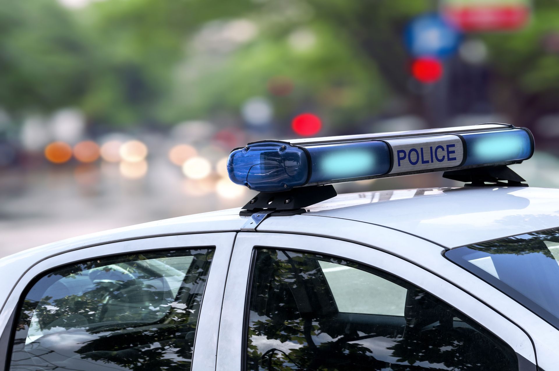 Police car with flashing blue lights on a city street at dusk