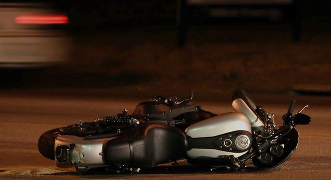 A black-and-white toy motorcycle lies on its side on a dimly lit road at night.