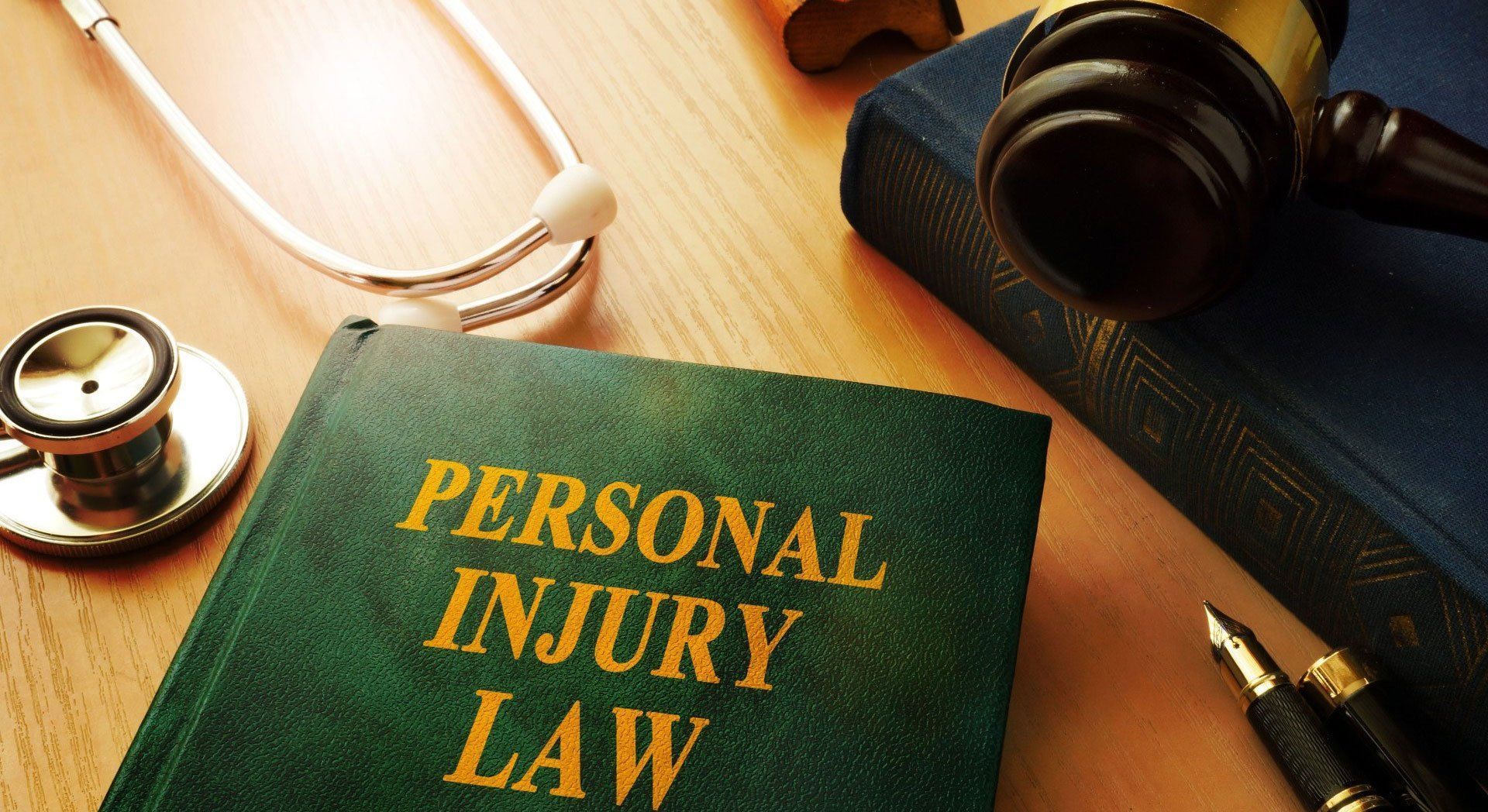 Personal injury law book on desk with stethoscope, camera, and pen