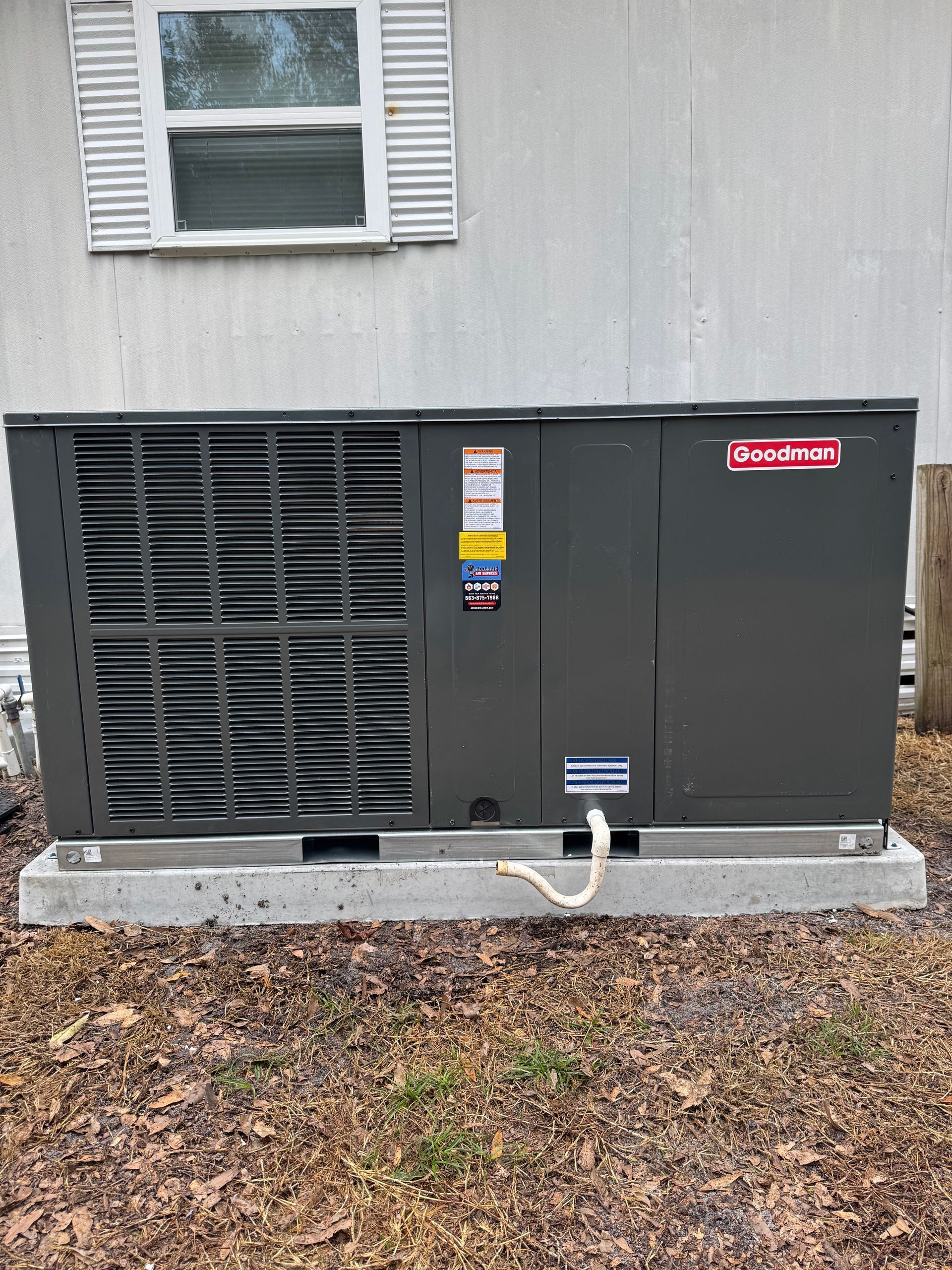 Gray outdoor generator unit beside a house, with vented panels and a red label.
