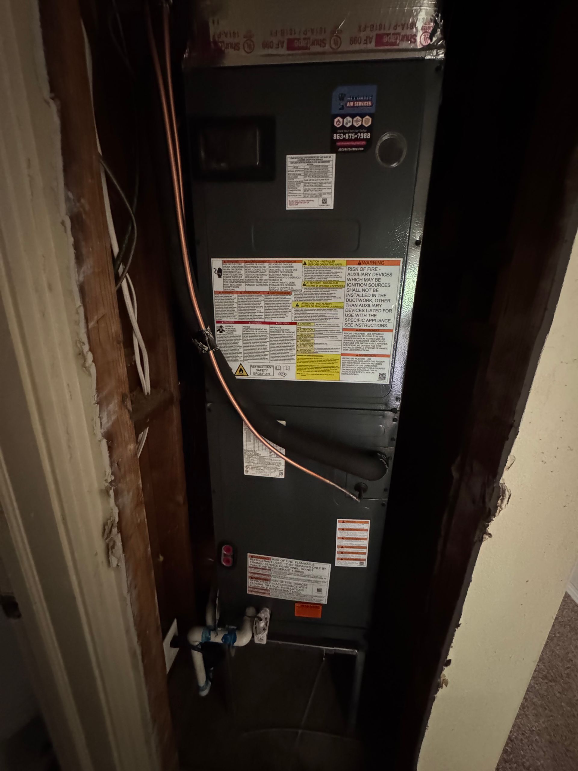 Open furnace unit in a narrow closet, with wiring and labels visible.