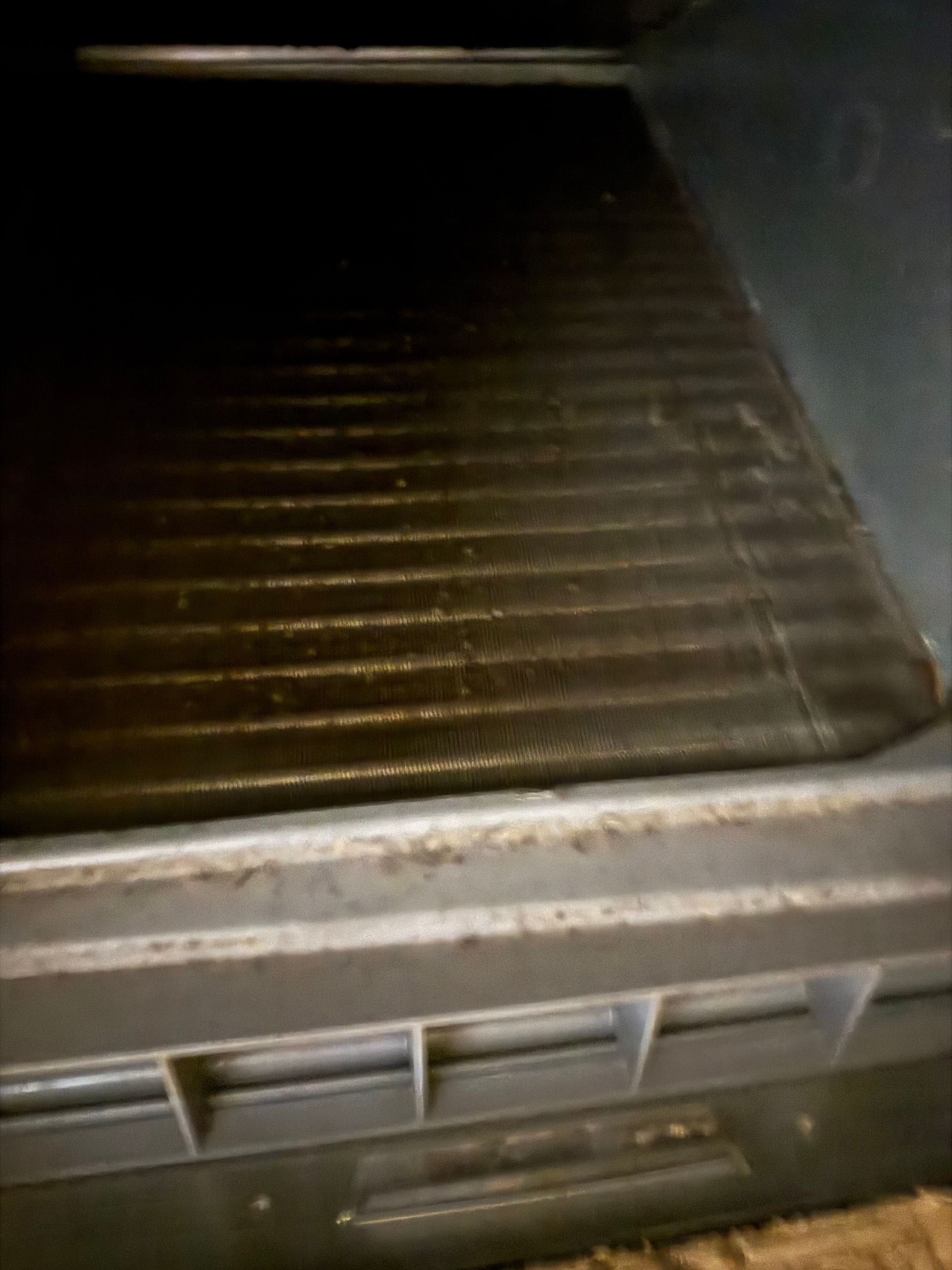 Empty metal grill or tray inside a dark appliance compartment