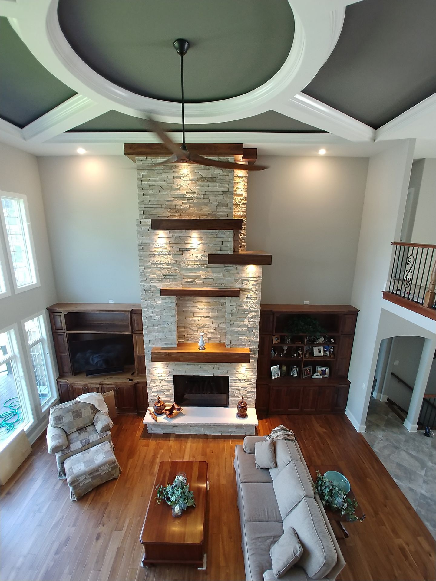 An aerial view of a living room with a fireplace and a ceiling fan
