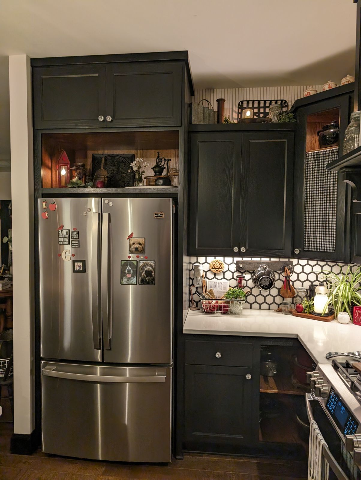 A kitchen with black cabinets and a stainless steel refrigerator