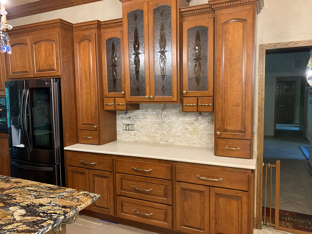 A kitchen with wooden cabinets , granite counter tops , and a refrigerator.