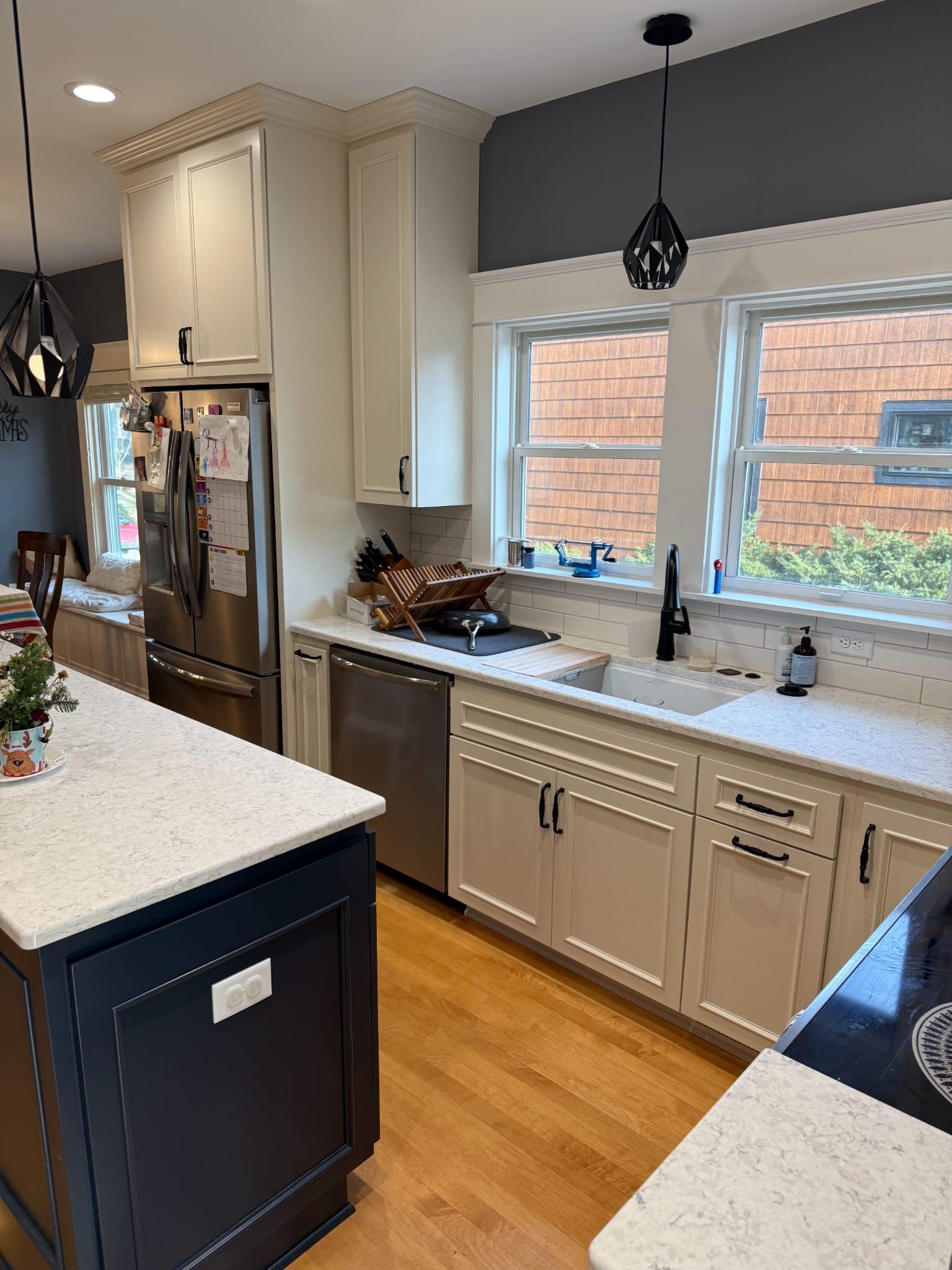 A kitchen with white cabinets , stainless steel appliances , a sink and a refrigerator.