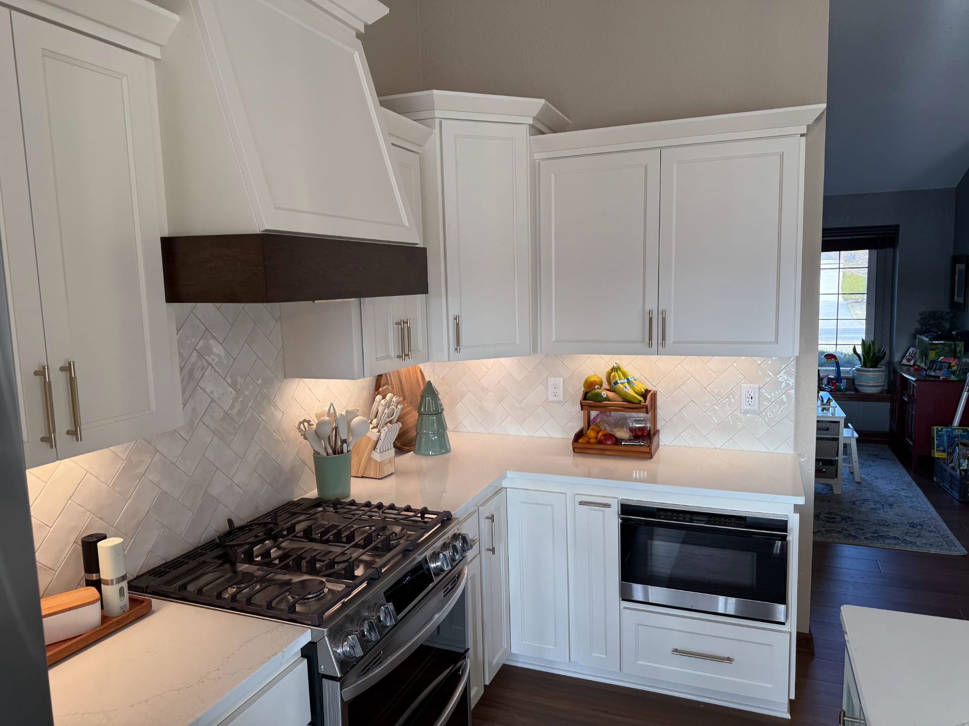 A kitchen with white cabinets , a stove and a microwave.