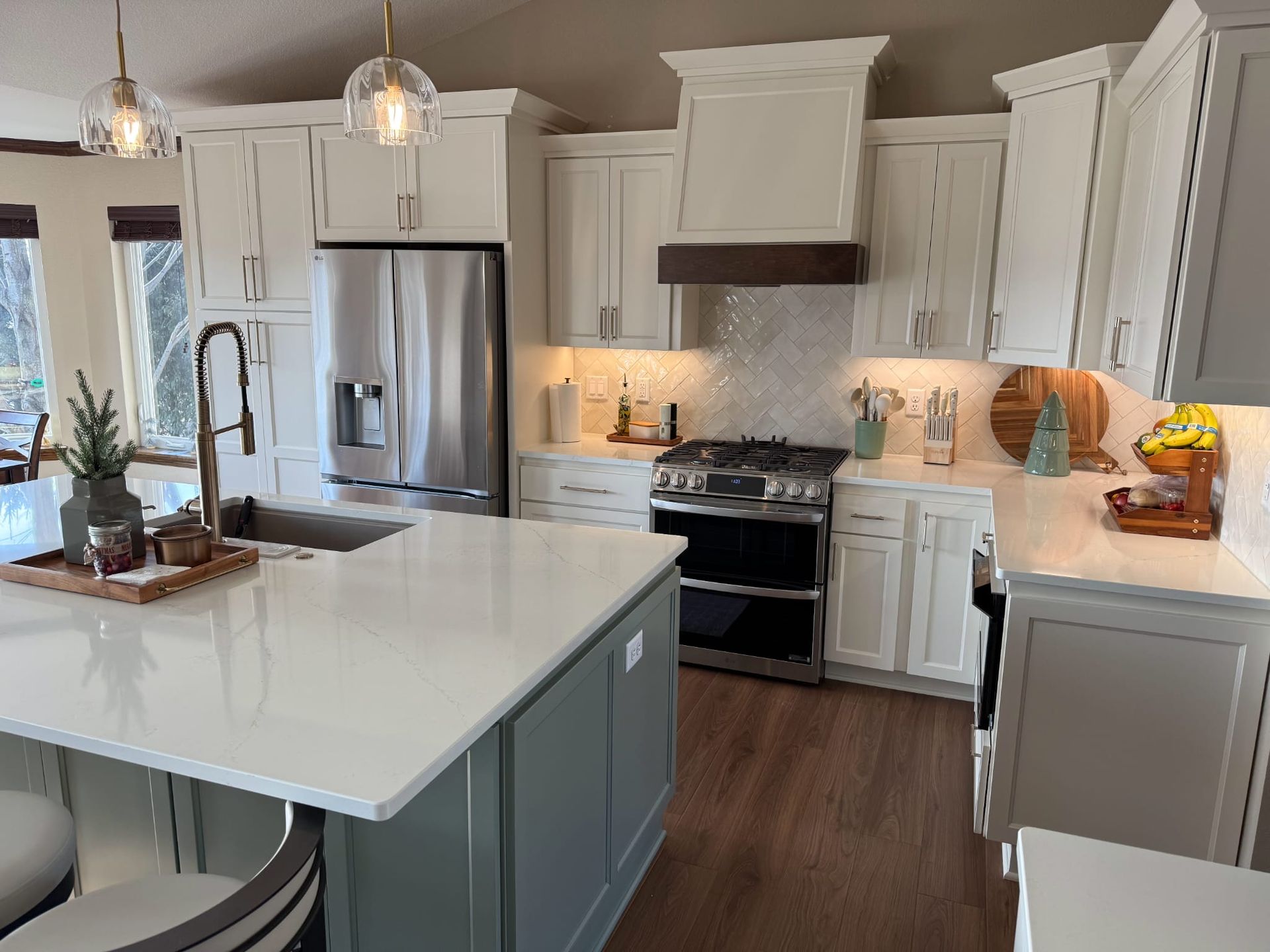A kitchen with white cabinets , stainless steel appliances , and a large island.