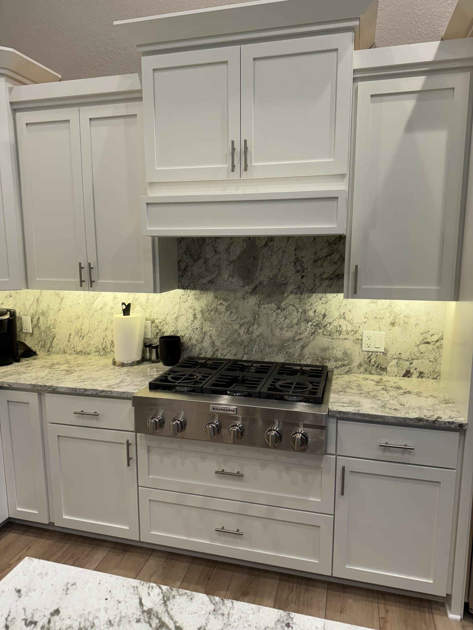 A kitchen with white cabinets and a stove top oven.