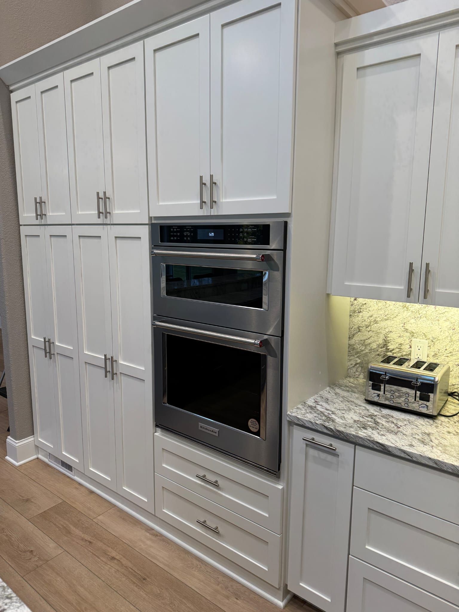 A kitchen with white cabinets and a stainless steel oven.