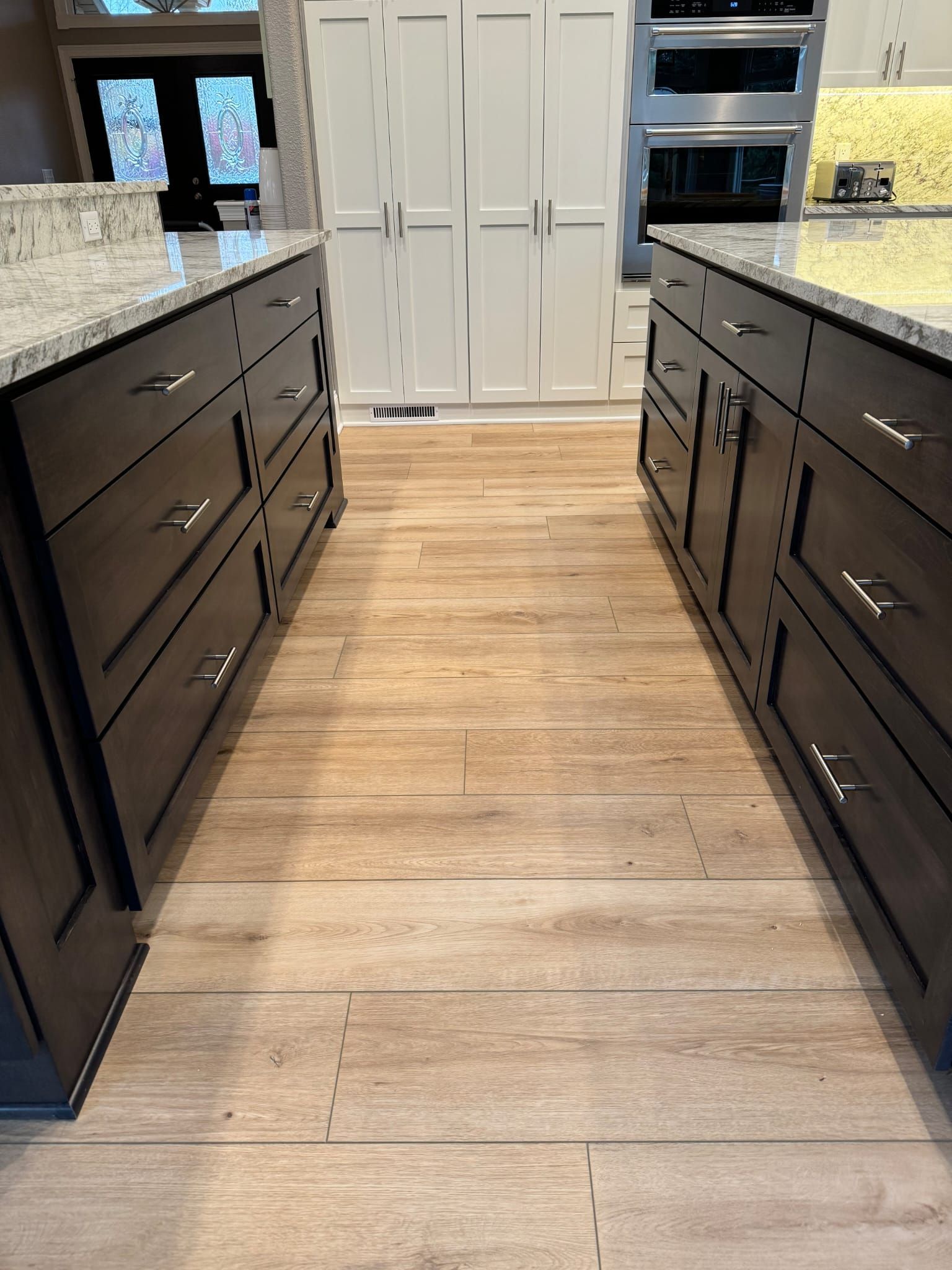 A kitchen with lots of cabinets and drawers and a wooden floor.