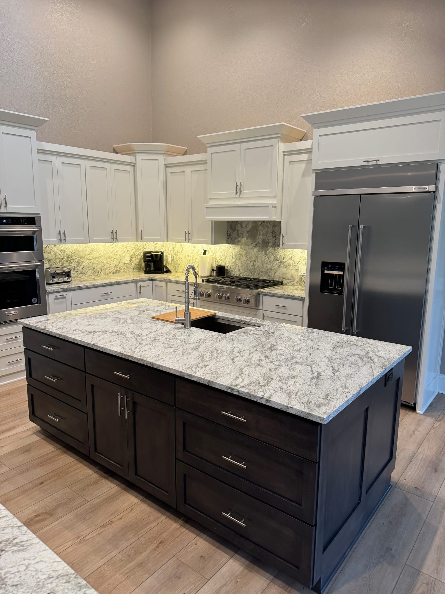 A kitchen with a large island in the middle and stainless steel appliances.