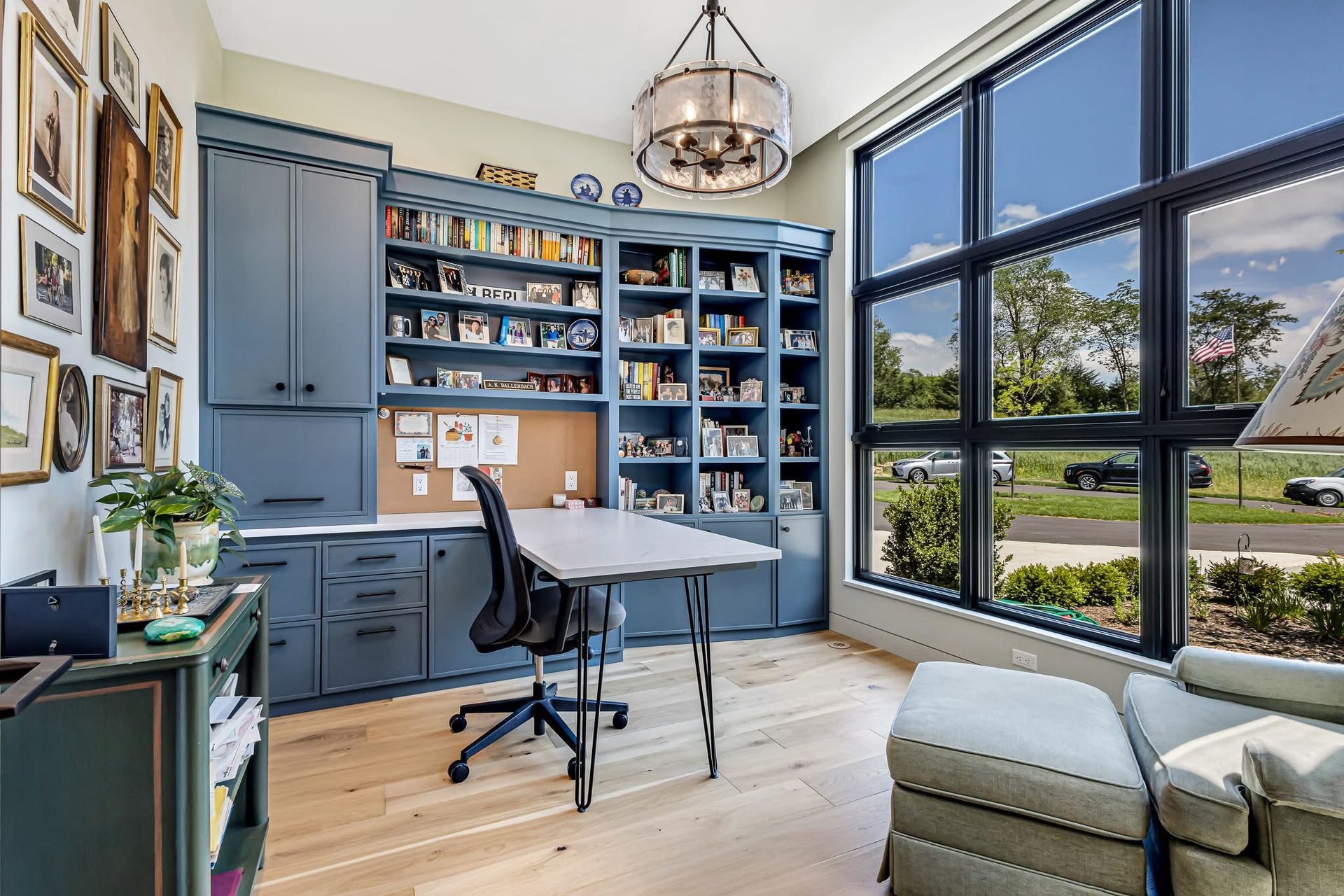Bright home office with blue built-ins, desk, chair, window wall, and light wood floors
