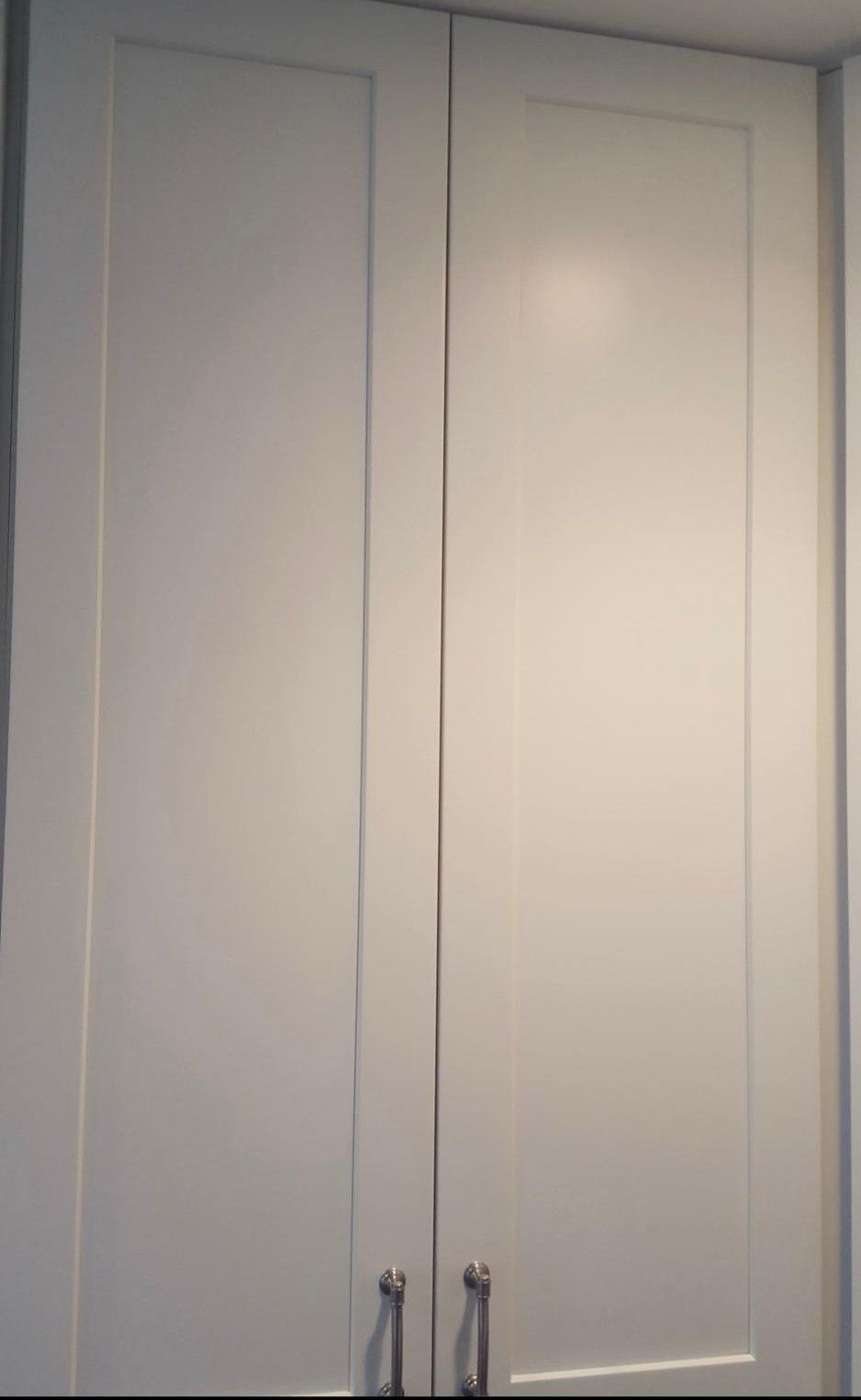 White double closet doors with silver handles in a room.