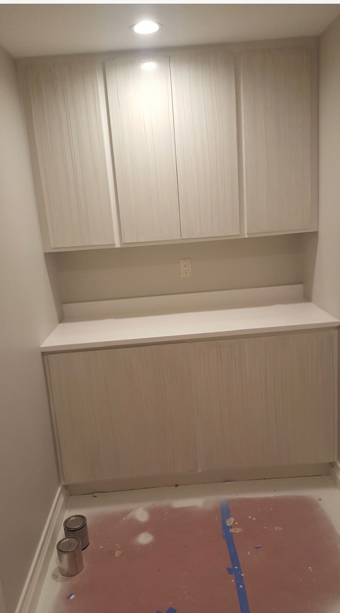 Small utility room with beige cabinets, countertop, and a work area covered in protective plastic.