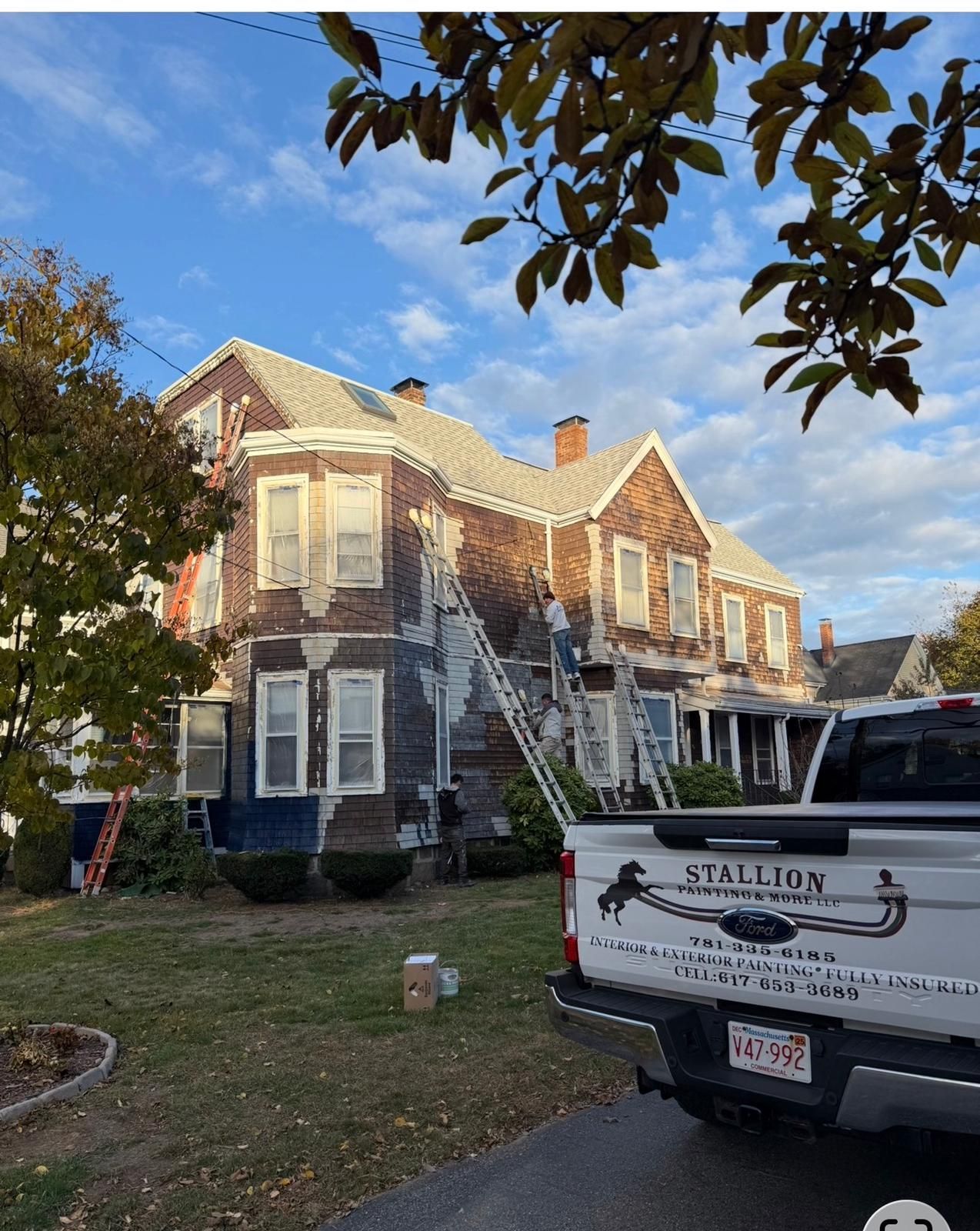 Brick house with white trim and a pickup truck parked in the driveway under a blue sky.
