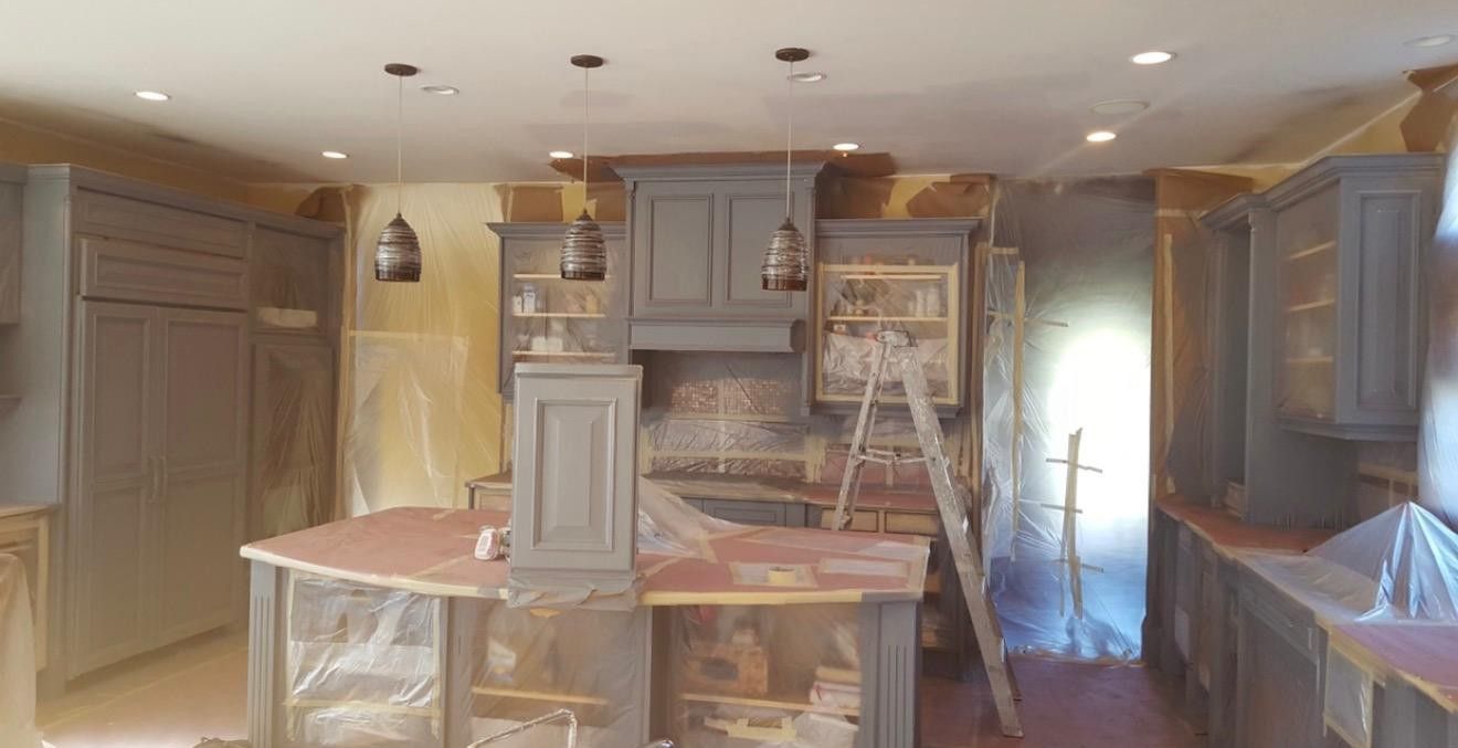 Kitchen under renovation with cabinets, island, ladder, and covered surfaces