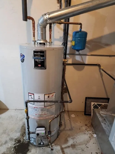 A tall, silver water heater with copper pipes and a blue expansion tank in a basement setting.