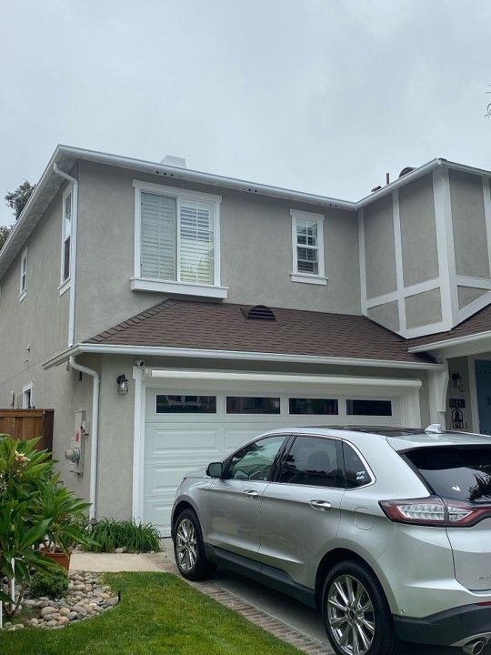 A silver car is parked in front of a large house.
