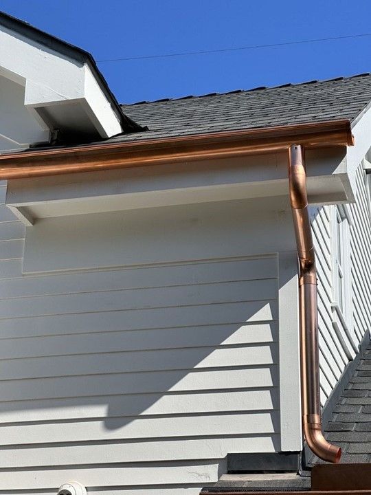 A white house with a copper gutter on the side.