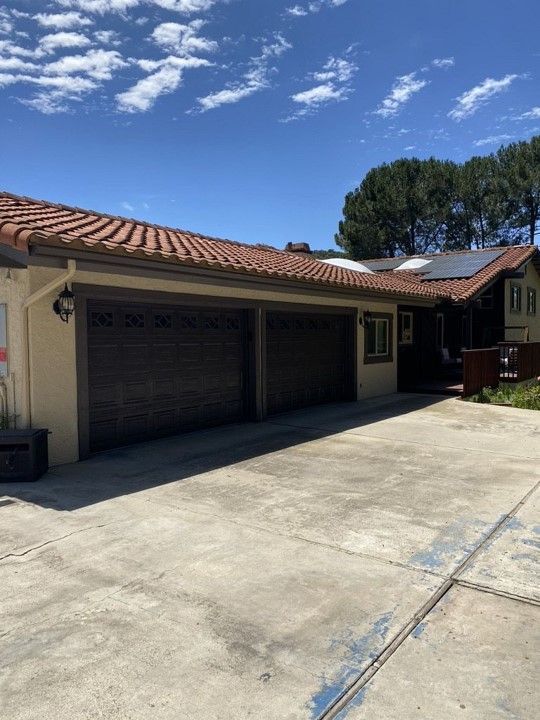 A house with a lot of garage doors and solar panels on the roof.