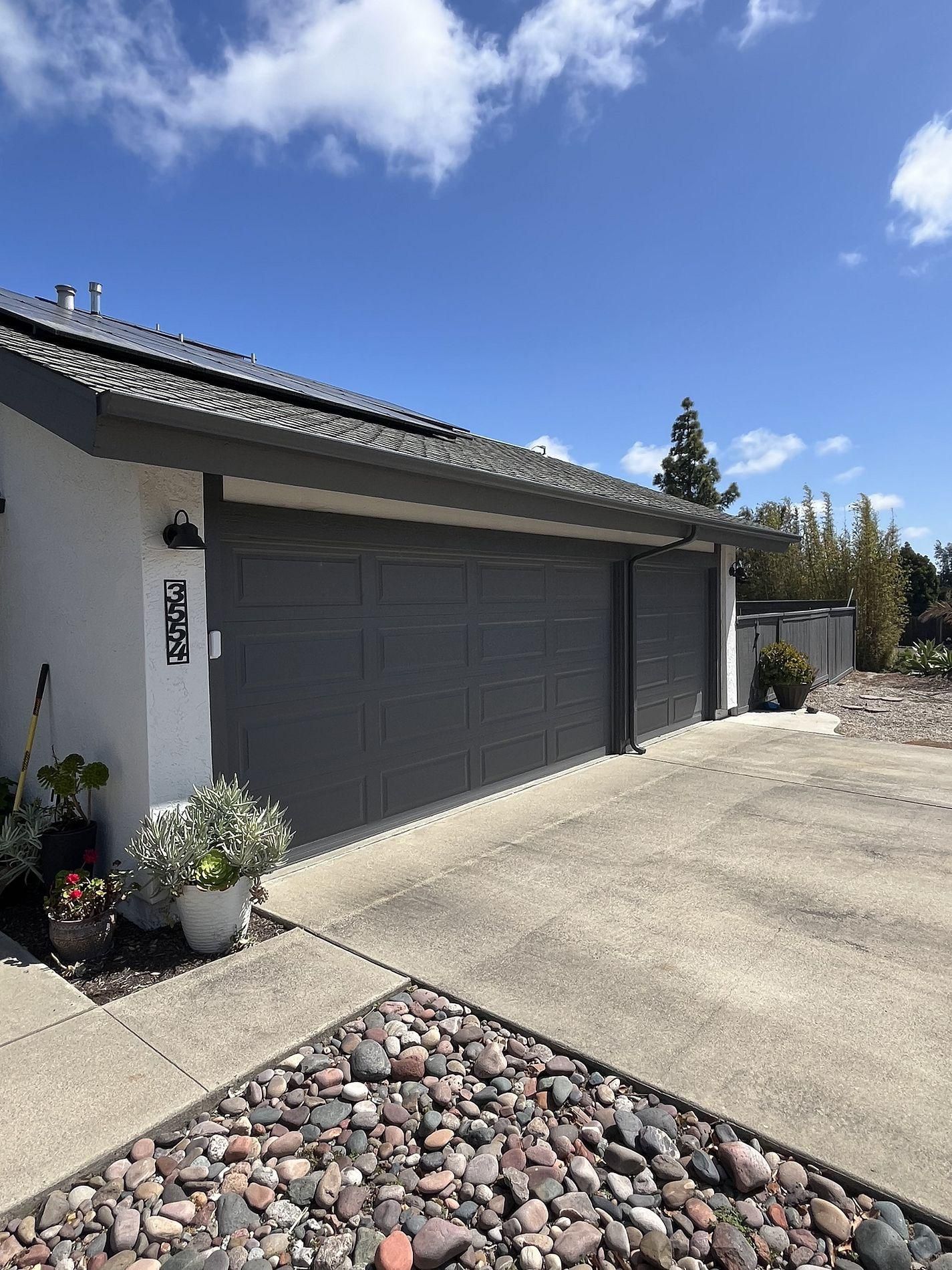 A house with a large garage door and a driveway with rocks in front of it.