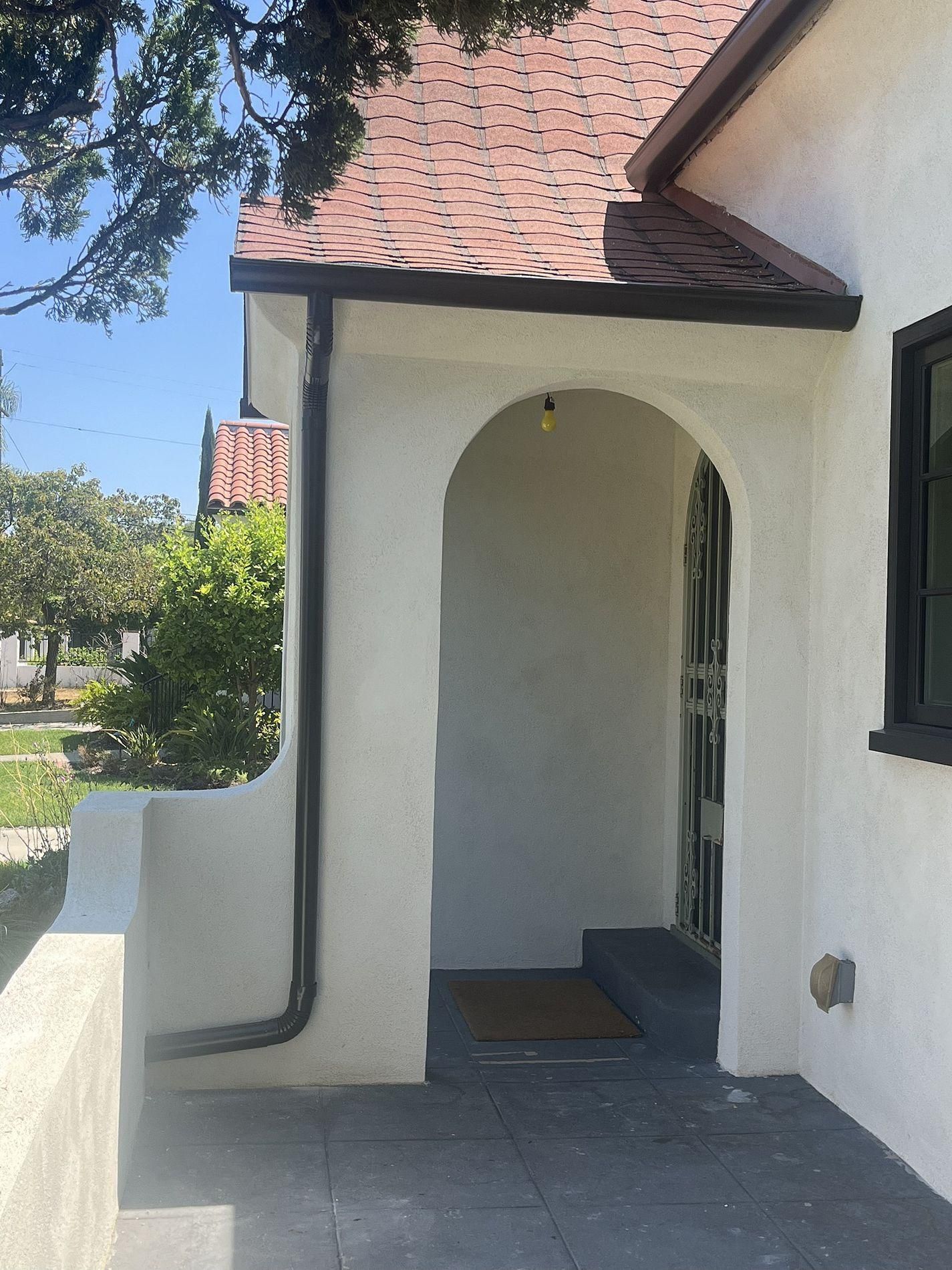 A white house with a red roof and a doorway.