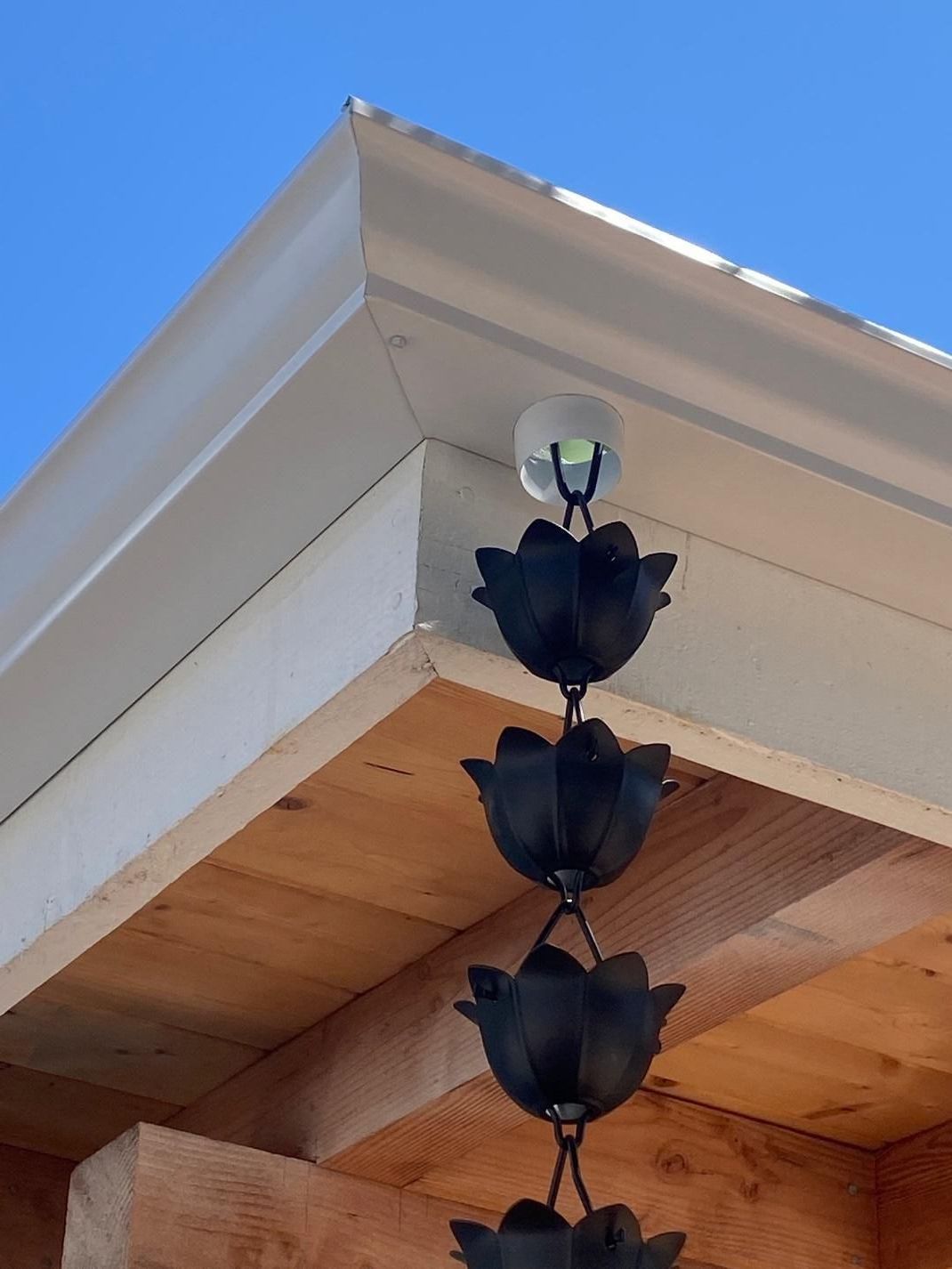 A wooden building with a white trim and black leaves on it.