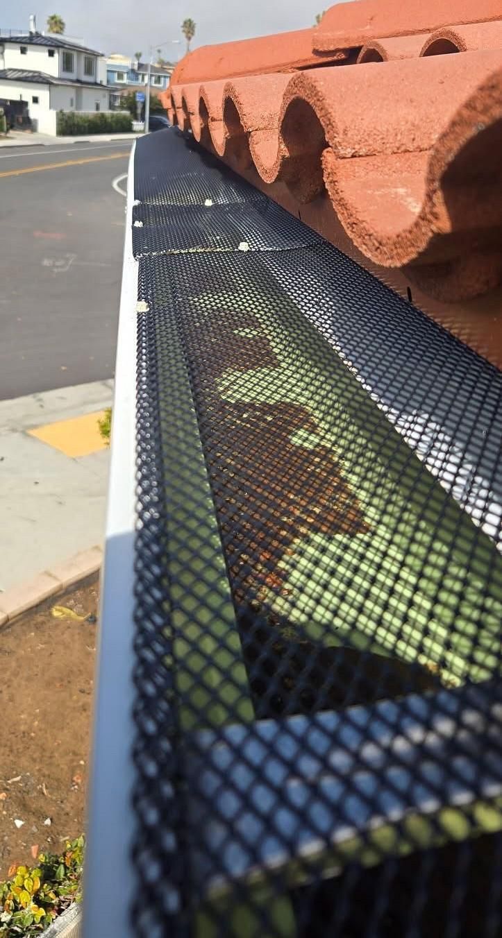 A close up of a gutter with a mesh on it.