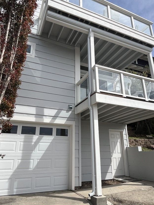 A white house with a white garage door and a balcony.