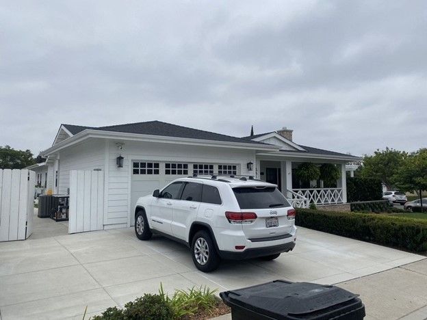 A white suv is parked in front of a white house.