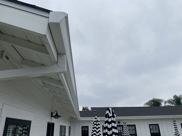 A white house with a black and white striped umbrella in front of it.