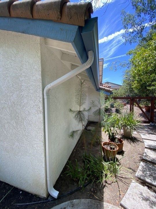 A white gutter is attached to the side of a house.